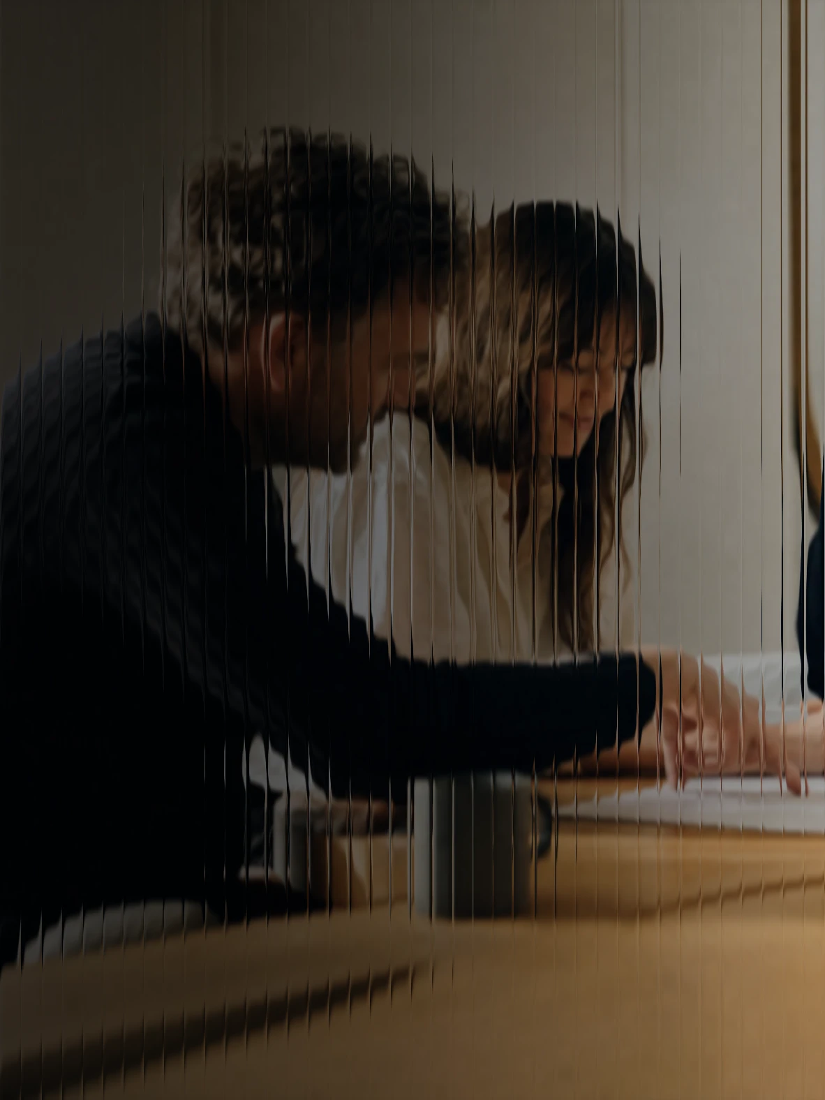 Three colleagues reading a document together at a long oak table